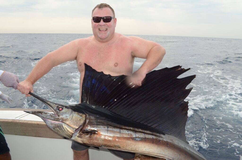 Angler holding a Pacific sailfish aboard a sportfishing boat in Central America.